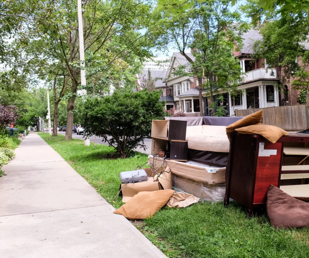 Pile of discarded furniture, mattress, and a dresser on a grassy verge awaiting junk removal in Northbridge, MA